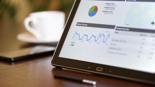 Fonds Anlagevorschläge - Tablet mit Statistiken neben Kaffeetasse und Smartphone auf einem Holztisch